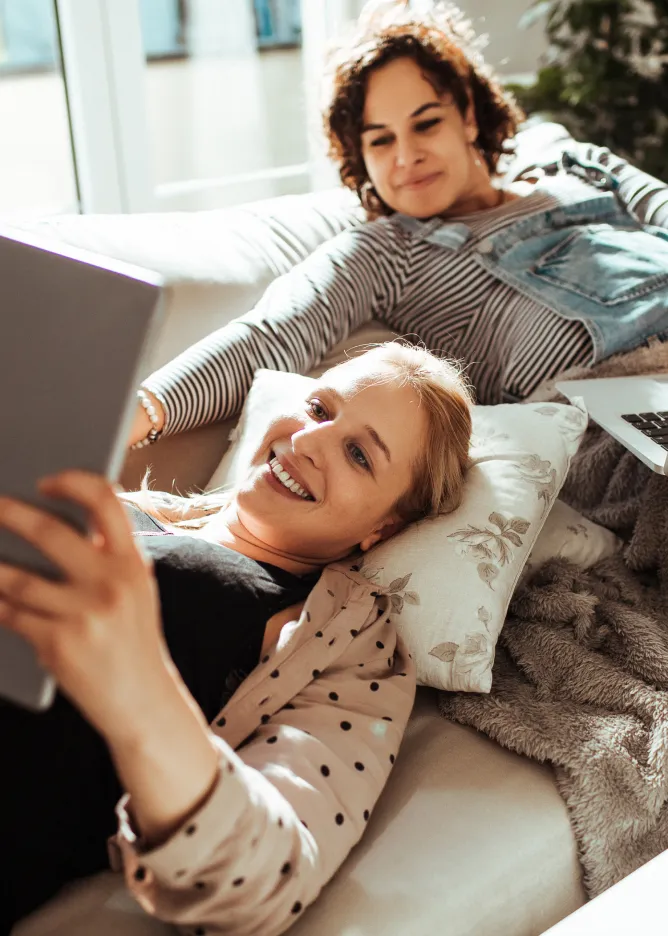 Two women looking at tablet on a couch